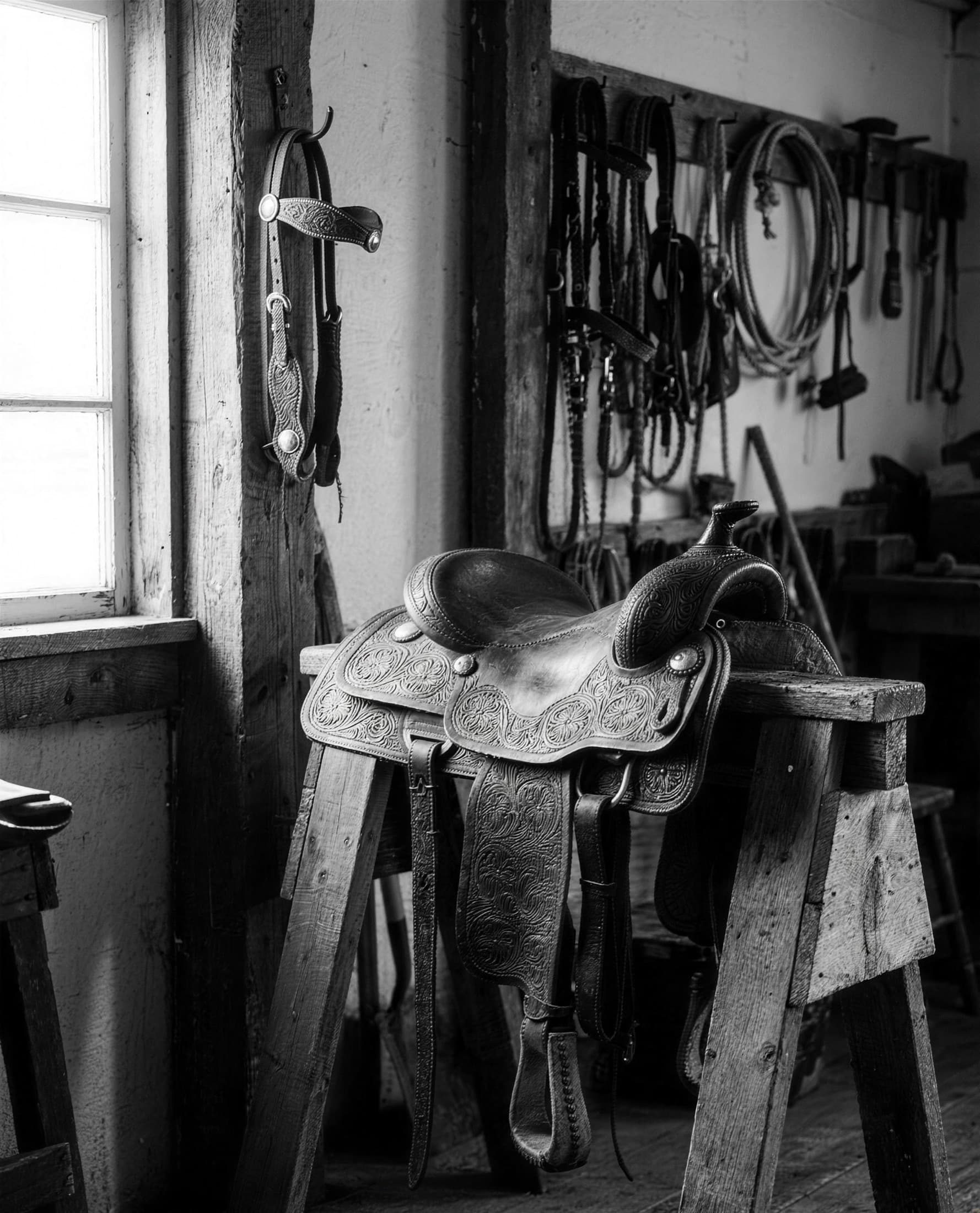 Hand-tooled western saddle and tack in a sunlit tack room